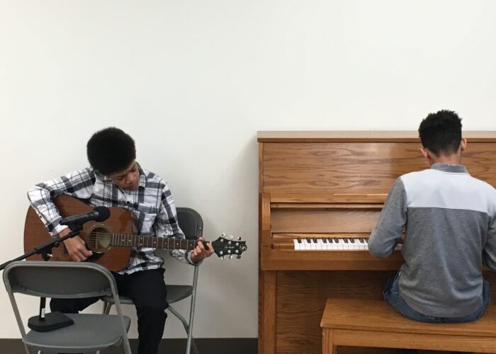 One man playing the guitar and another man playing the piano